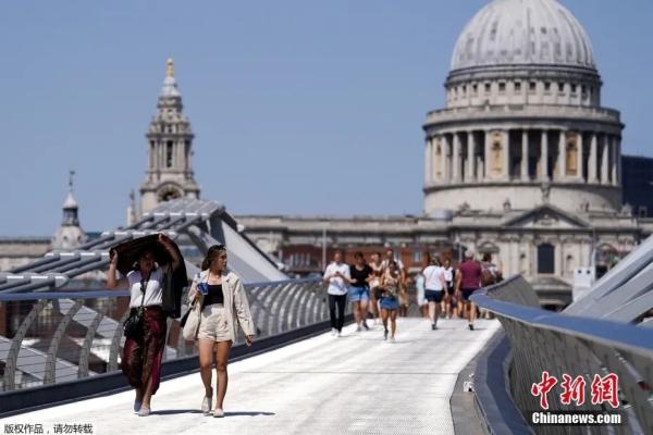 热浪来袭,人们在伦敦千禧桥上遮挡太阳前行。图片来源:中国新闻网 热浪来袭,人们在伦敦千禧桥上遮挡太阳前行。图片来源:中国新闻网